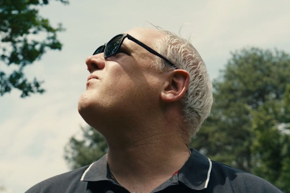 Ali outside wearing sunglasses and looking at the sky