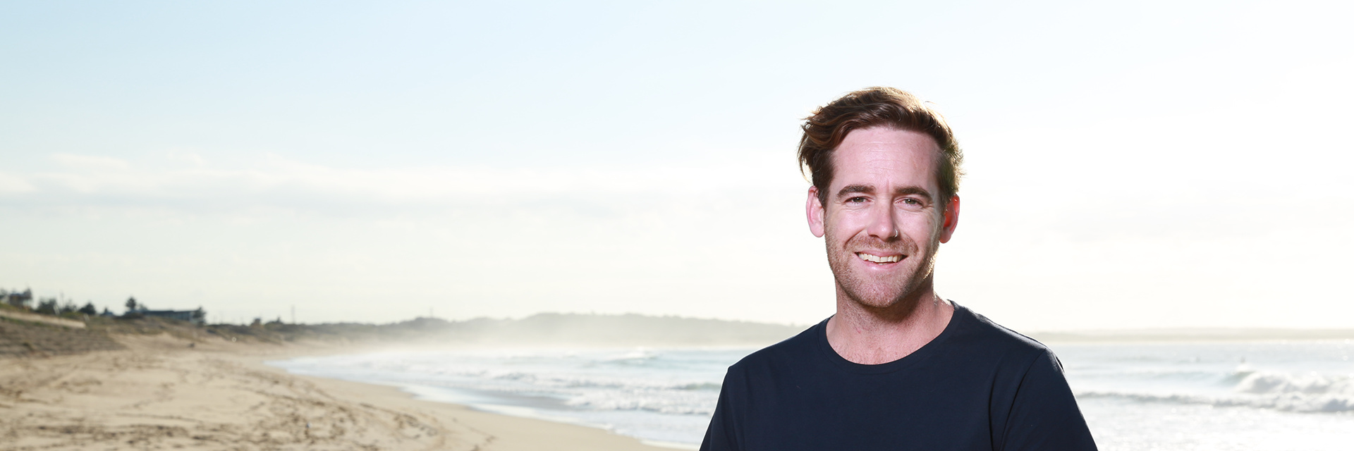 Mark standing on the beach, looking to camera