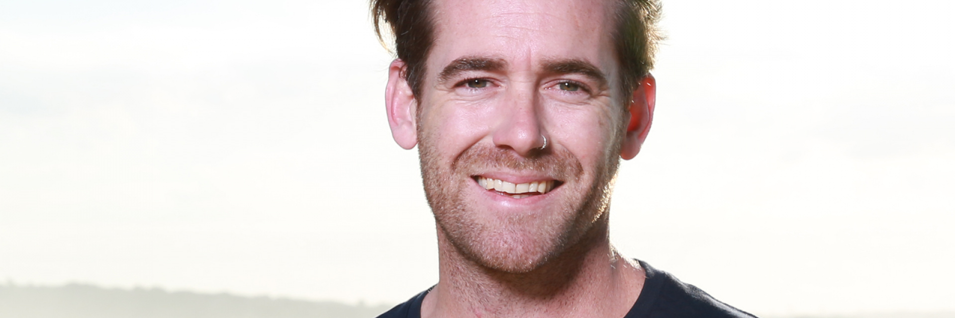 Mark standing on the beach, looking to camera