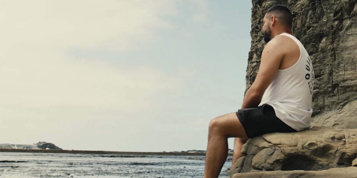 Nathan sitting on rocks looking out at the ocean