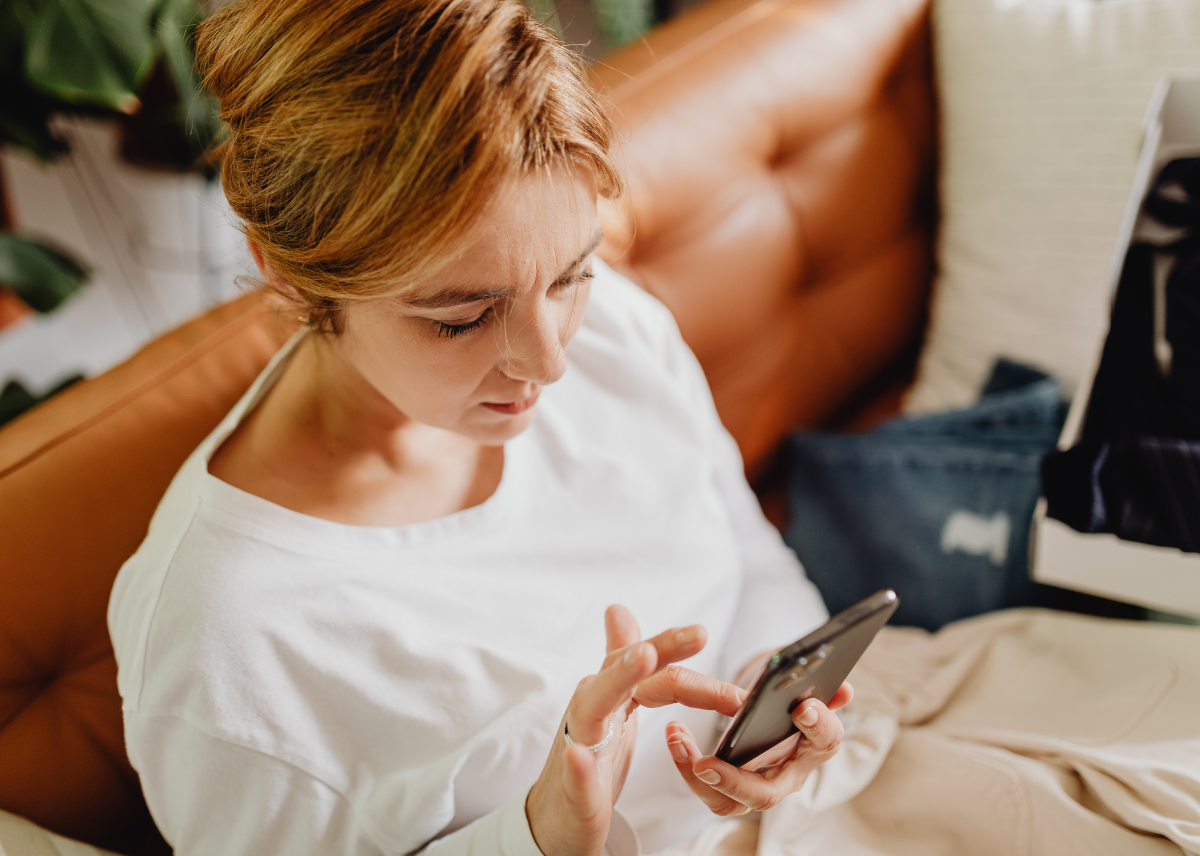 Caucasian women in her late 40s, sitting on a tanned leather sofa and researching information online