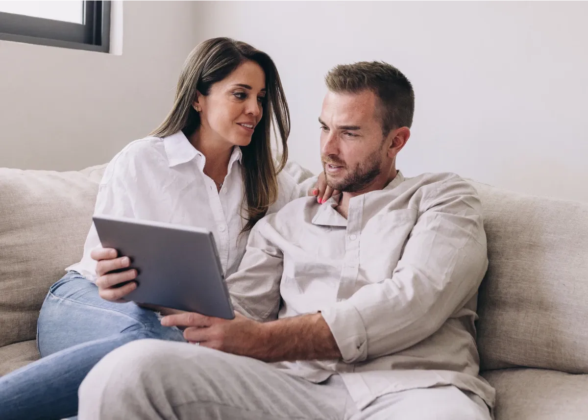 Heterosexual couple in their 30s, sitting on the couch and completing a Beyond Now safety plan on their tablet.